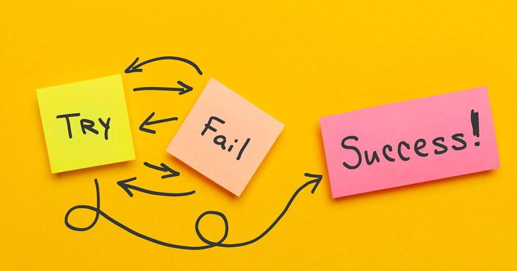 3枚の付箋が並んでいる。左から順に『TRY』『Fail』『Success!』と書かれており、『TRY』と『Fail』の間には複数の矢印が行き来している。そこから複雑に曲がりくねった矢印が『Success!』に到達しており、試行錯誤の末に成功へ至ることを表現したビジュアル。