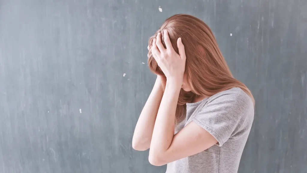 頭を抱えて悩む女性の画像