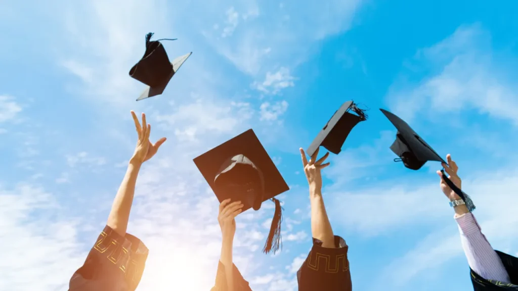 卒業で帽子を空に向かって投げている画像