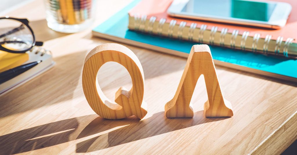 「QA」の木製ブロックが並んだデスクのビジュアル。