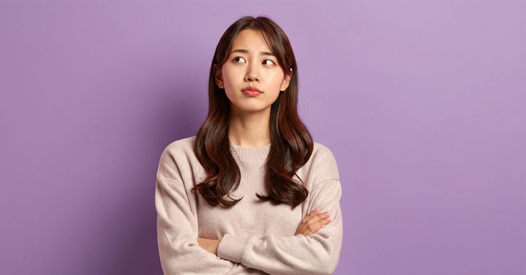 疑いの表情を浮かべる女性のイメージ画像。