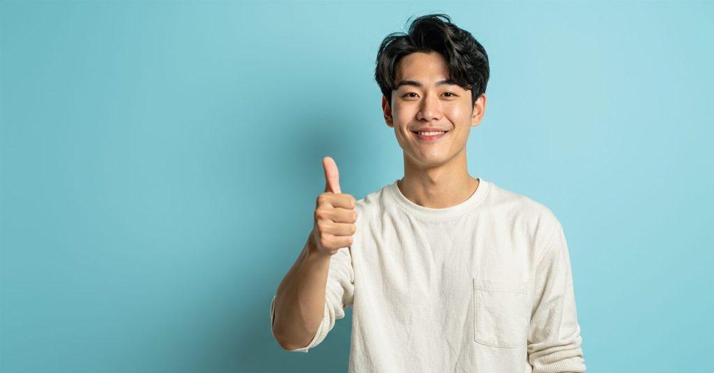 グッドポーズで笑顔を浮かべる青年のビジュアル。