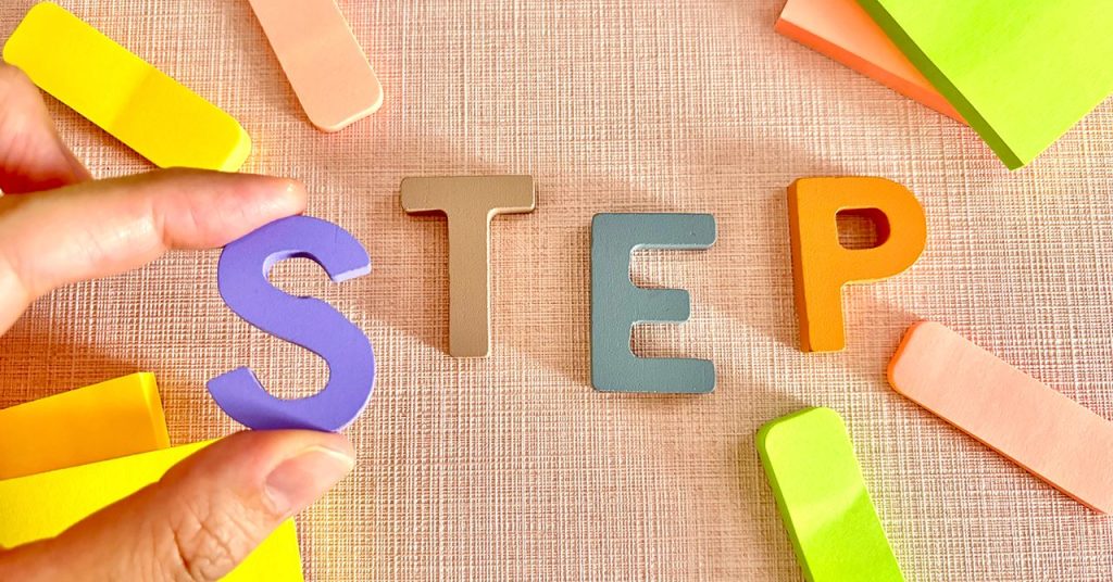 「STEP」という文字のカラフルな木片とカラフルな付箋が散らばったイメージビジュアル。