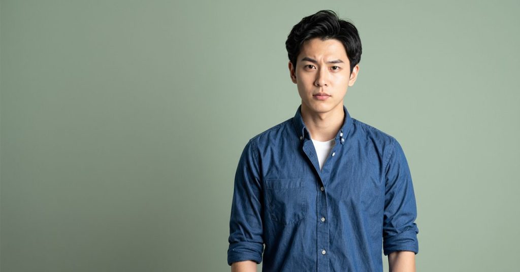 眉間に皺を寄せ険しい表情を浮かべる青年のビジュアル。